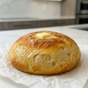 A round loaf of Dolly Parton Crock Pot Bread topped with a pat of melting butter