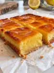 Golden baked 2 ingredient lemon bars cut into squares on parchment with a creamy lemon center