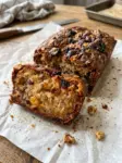 Sliced banana raisin bread with walnuts and golden and dark raisins on parchment