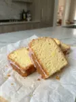 Slices of glazed lemon loaf with a tender golden crumb and lemon glaze on parchment