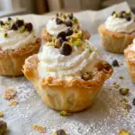 Mini cannoli cups filled with swirled ricotta cream and topped with mini chocolate chips, pistachios and powdered sugar
