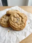 Soft Salted Honey Cookies with Brown Sugar & Cinnamon 6 A stack of soft salted honey cookies with brown sugar and cinnamon, topped with flaky sea salt on parchment paper